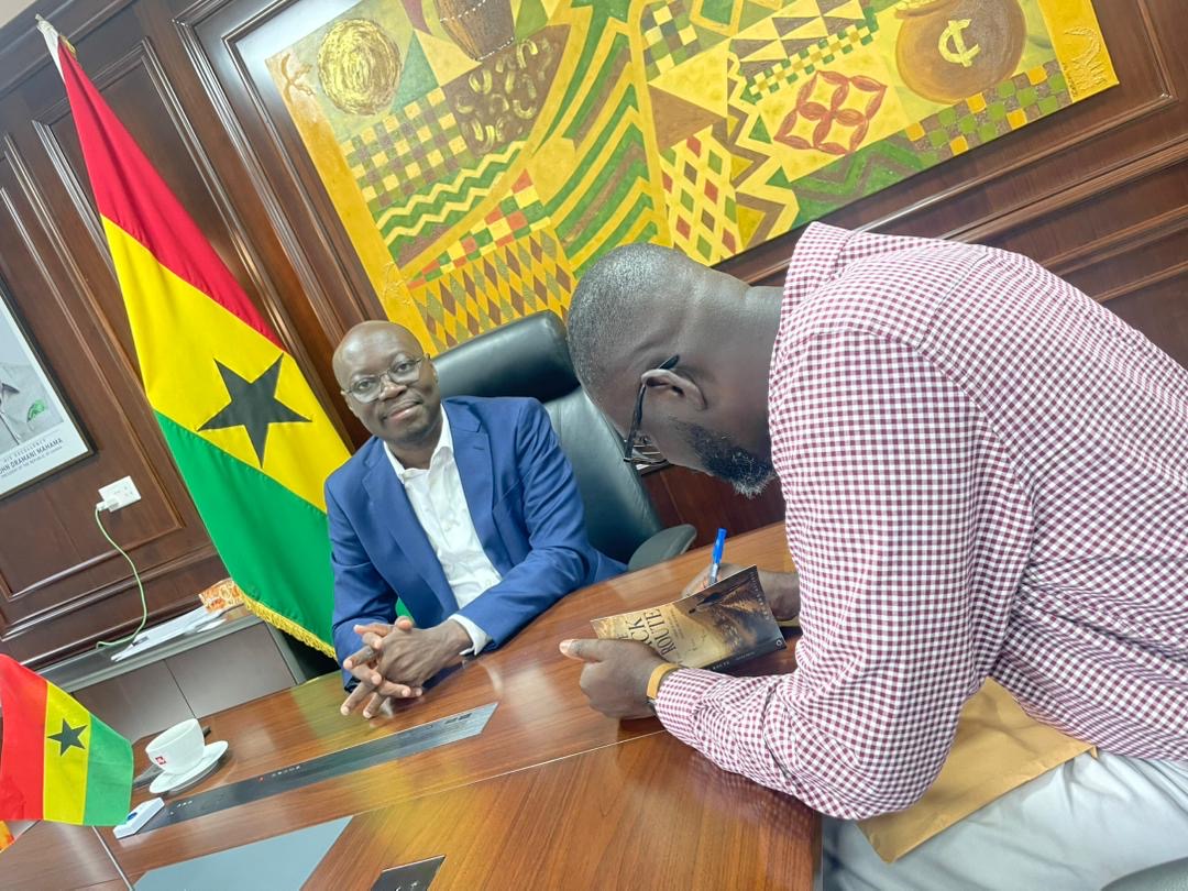 Dr George Asiamah signing a copy of The Back Route for Dr Cassiel Ato Forson